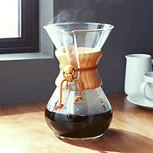A Chemex carafe filled with freshly brewed pour over coffee, featuring its signature wooden collar and leather tie, an ideal vessel for a clean and aromatic coffee experience.